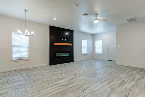 a view of an empty room with window and wooden floor