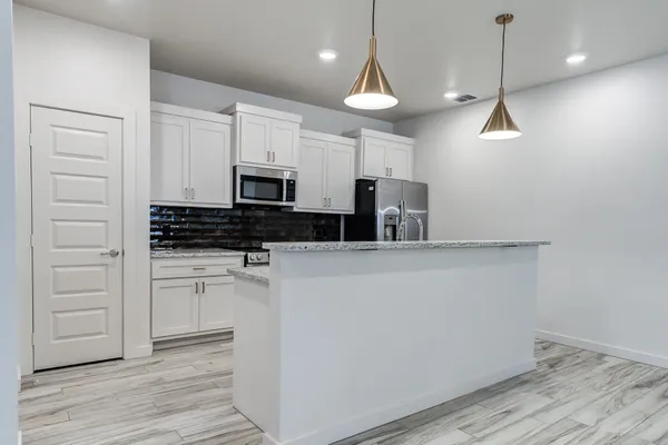 a kitchen with a refrigerator a stove and white cabinets with wooden floor