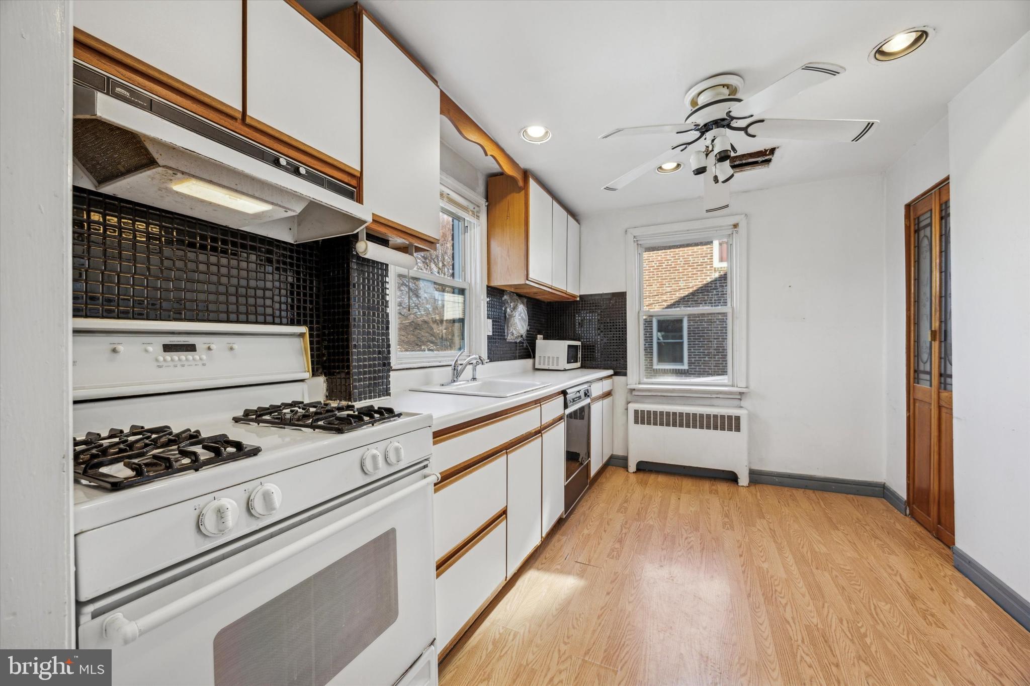 2044 Jenkintown Road Glenside, PA 19038 - Photo 13 of 33 a kitchen with stainless steel appliances a stove a sink and white cabinets with wooden floor