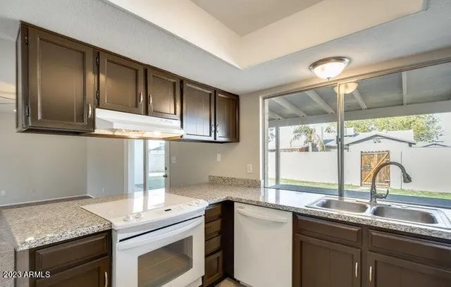 a kitchen with granite countertop stainless steel appliances a sink stove and cabinets
