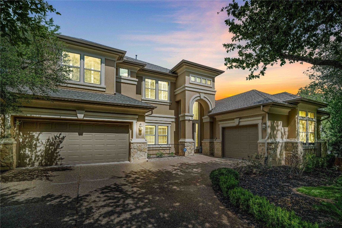 Prairie-style house with driveway, stucco siding, roof with shingles, and stone siding
