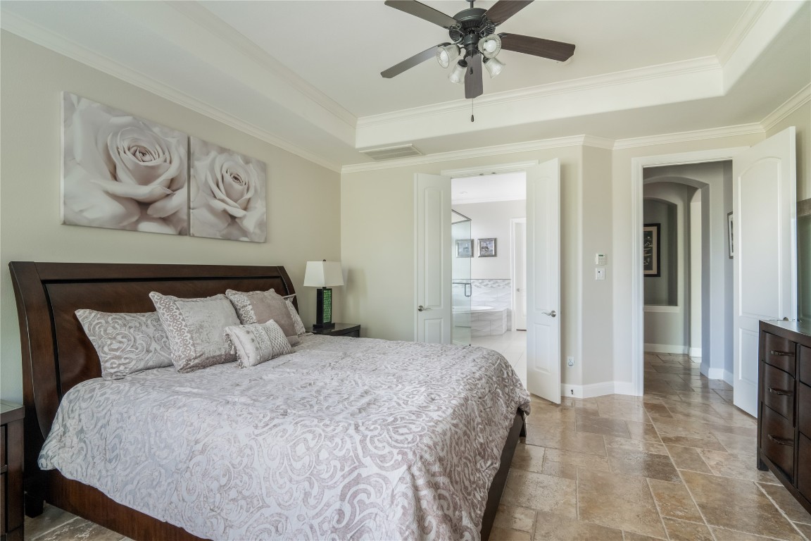 13301 Country Trails Lane Austin, TX 78732 - Photo 12 of 40 Primary Bedroom with a raised ceiling, stone tile flooring, ornamental molding, arched walkways, and ensuite bath