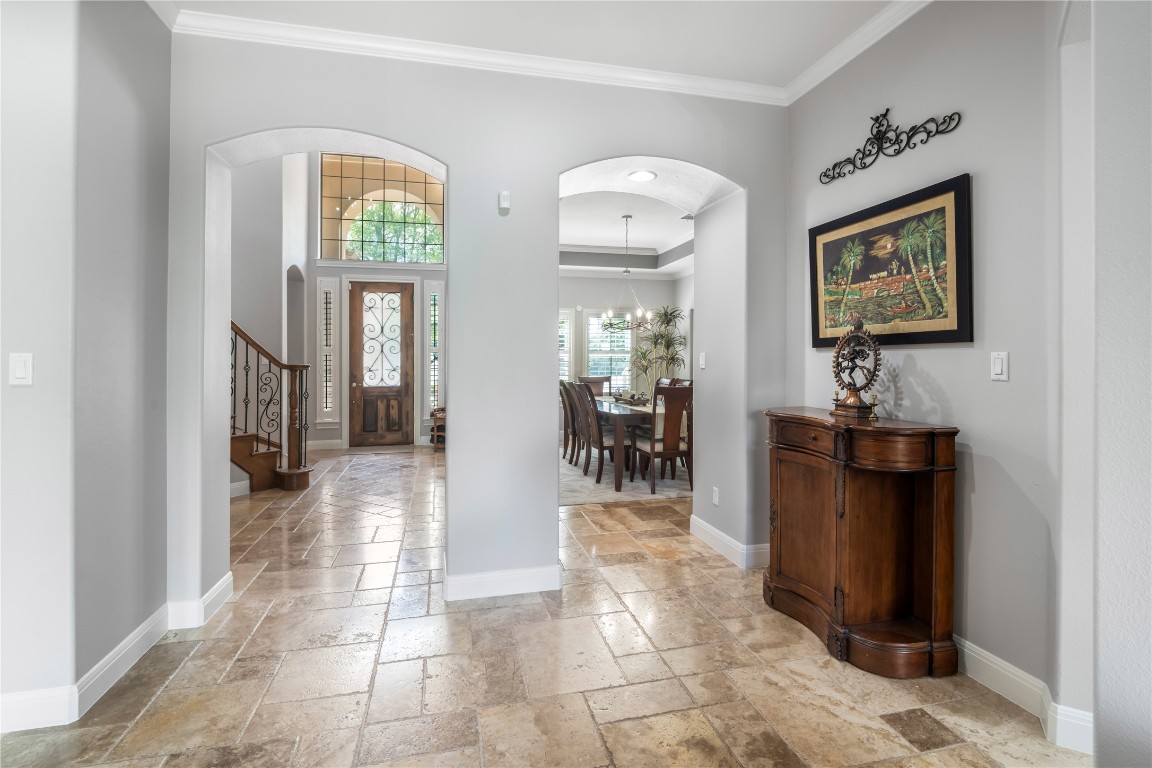 13301 Country Trails Lane Austin, TX 78732 - Photo 17 of 40 Entrance foyer with stone tile flooring, crown molding, arched walkways, and stairway