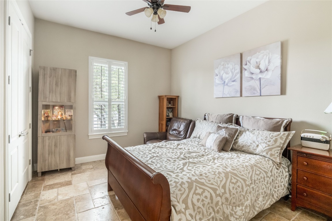 13301 Country Trails Lane Austin, TX 78732 - Photo 18 of 40 Main floor guest bedroom with stone tile floors and ceiling fan