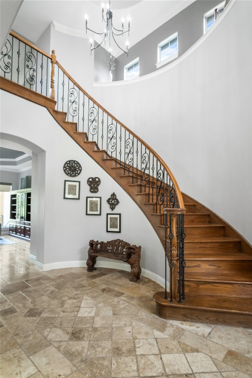 13301 Country Trails Lane Austin, TX 78732 - Photo 6 of 40 Foyer with curve Stairway featuring stone tile flooring, a high ceiling, a chandelier, arched walkways, and crown molding