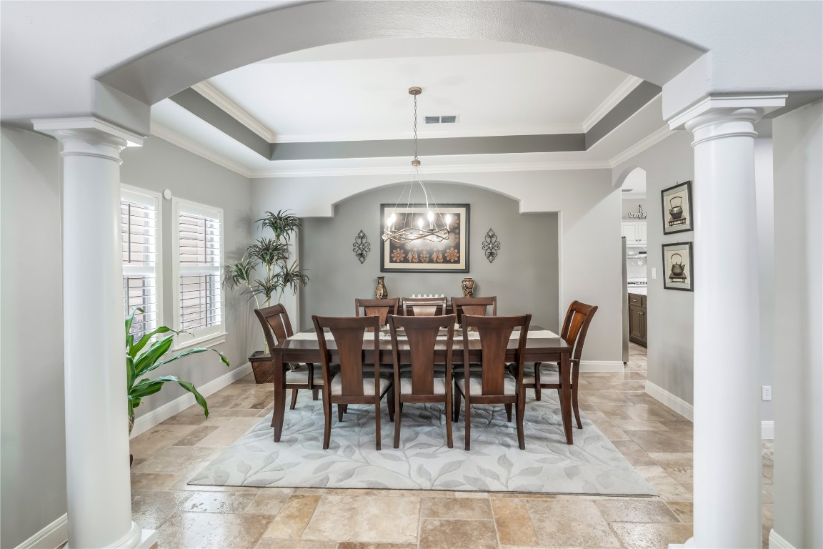 13301 Country Trails Lane Austin, TX 78732 - Photo 7 of 40 Dining area with ornate columns, stone tile flooring, a tray ceiling, ornamental molding, and arched walkways
