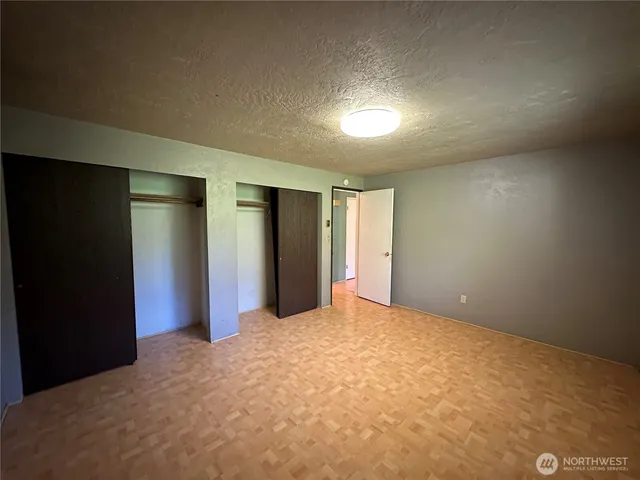 a view of an empty room with closet and a bathroom