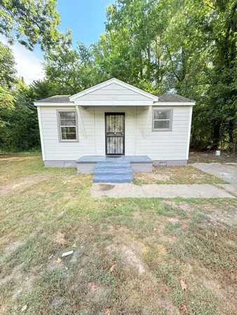a front view of house with yard and trees in the background