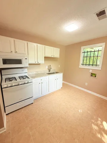 a kitchen with stainless steel appliances granite countertop a stove a sink and a microwave