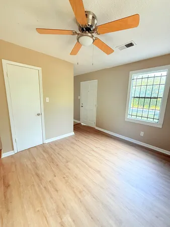 an empty room with windows and fan