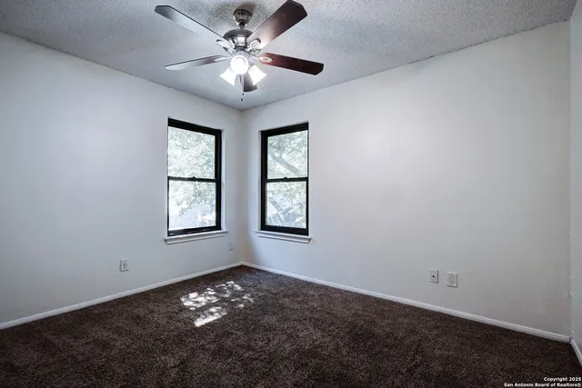 en empty room with windows and ceiling fan