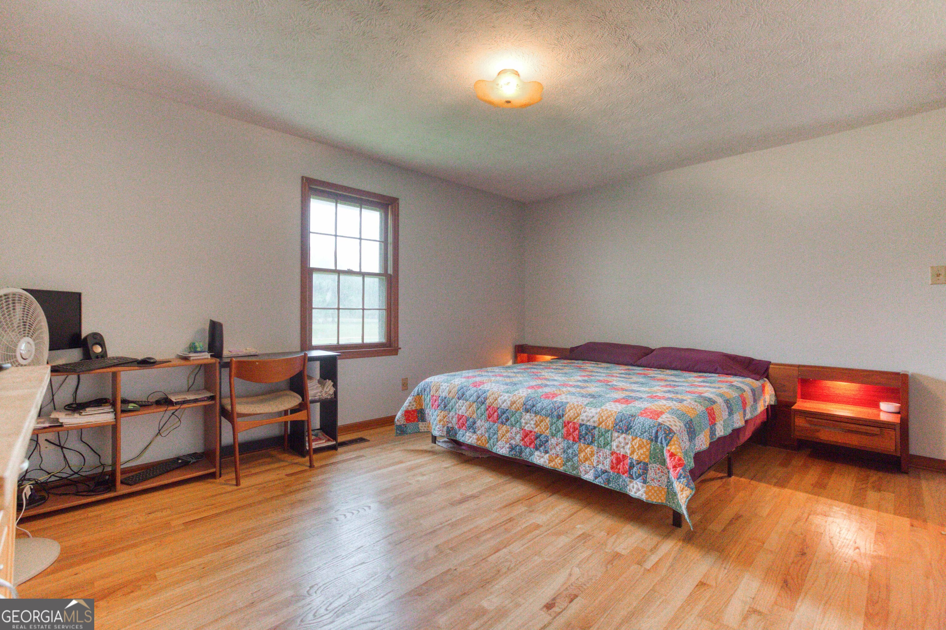 2141 Greensboro Road Madison, GA 30650 - Photo 29 of 35 a bedroom with a bed and wooden floor
