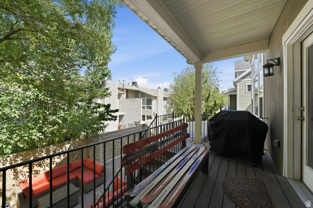 7872 Farm House Lane Midvale, UT 84047 - Photo 31 of 39 Covered outdoor deck with composite decking, white trim, and a black metal railing