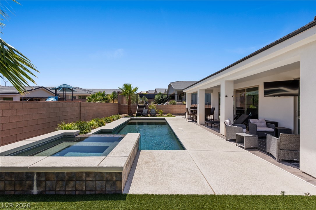 1436 Manassas Ridge Mesquite, NV 89027 - Photo 53 of 77 An inviting backyard oasis offers a sparkling pool, integrated spa, and spacious covered patio perfect for outdoor enjoyment.