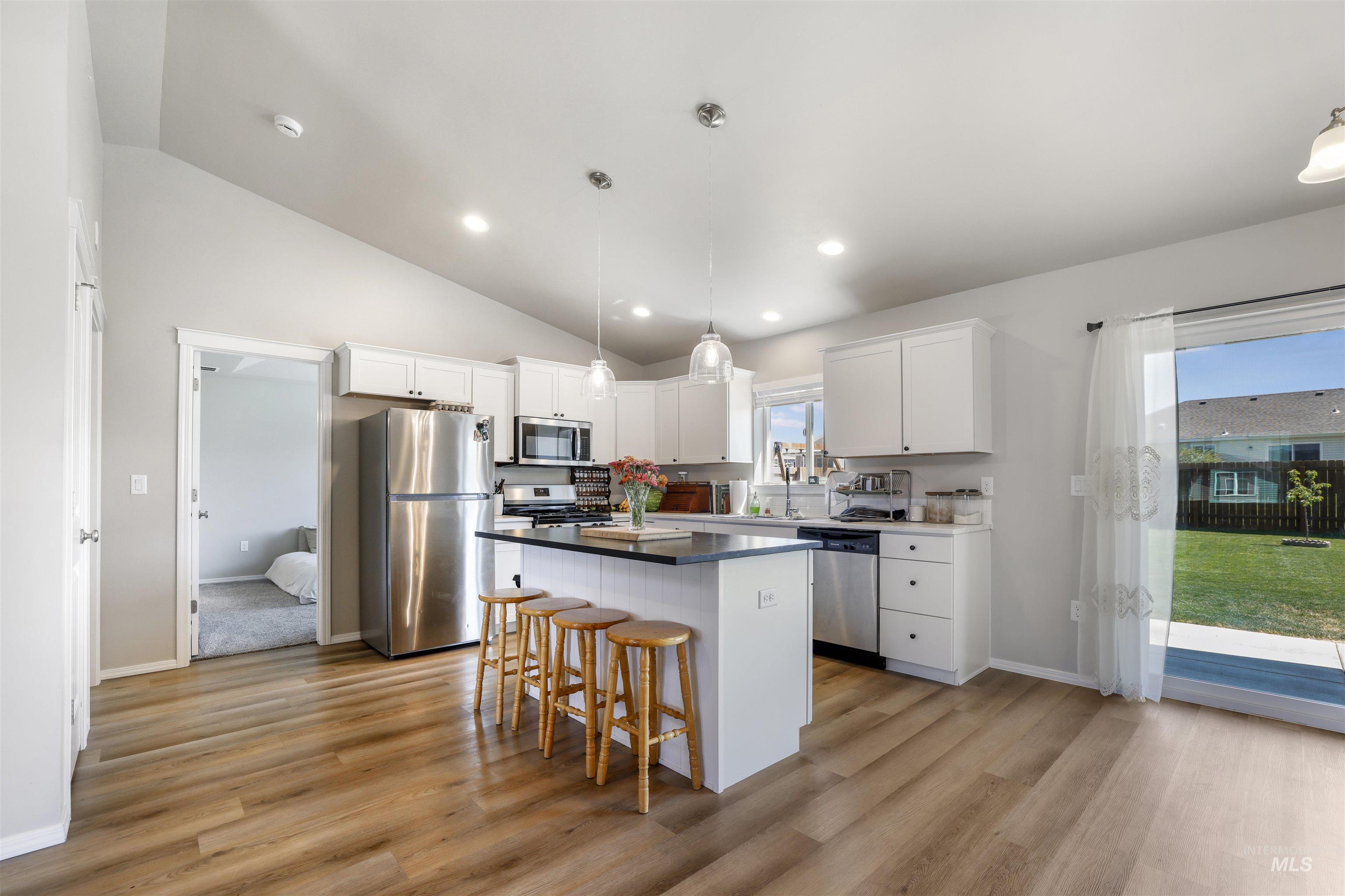 1113 Meadow Lake Loop Buhl, ID 83316 - Photo 5 of 15 Kitchen with a breakfast bar area, appliances with stainless steel finishes, a center island, decorative light fixtures, and white cabinetry