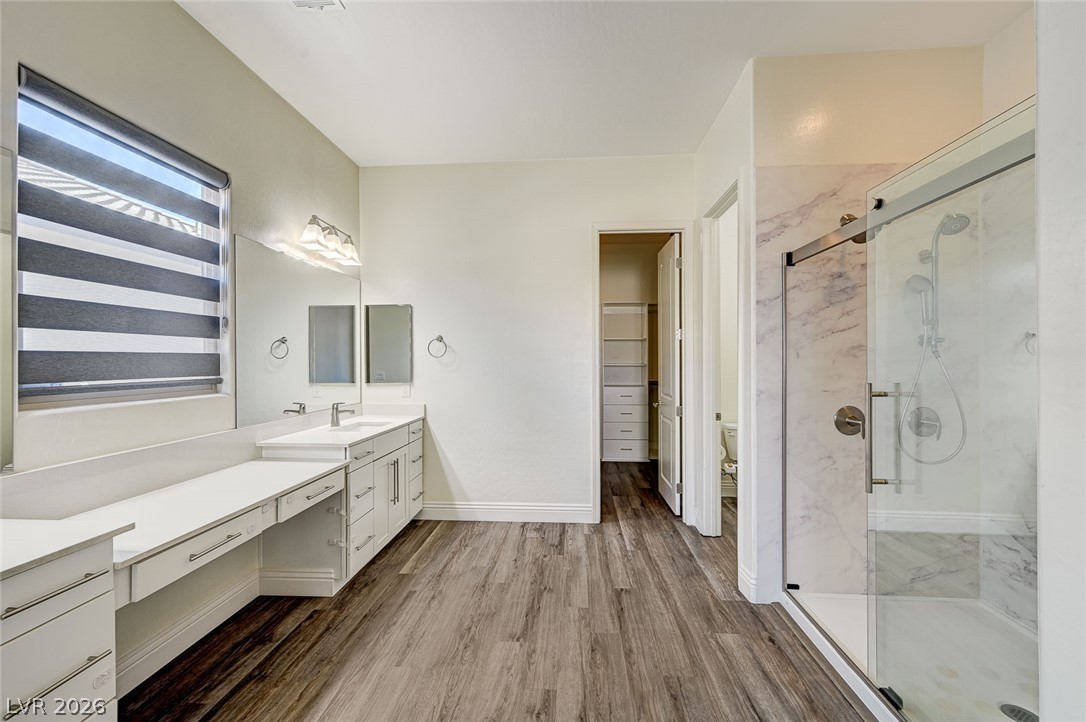 8197 Riley Love Street Las Vegas, NV 89139 - Photo 29 of 48 A refined primary bathroom offering double vanity, marble shower, and spacious wood plank flooring.