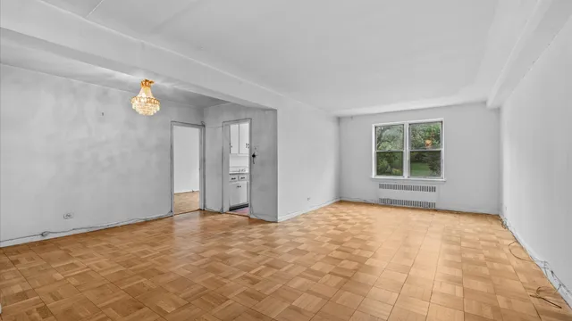 a view of an empty room with window and wooden floor