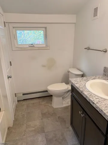 a bathroom with a granite countertop sink a toilet and a window