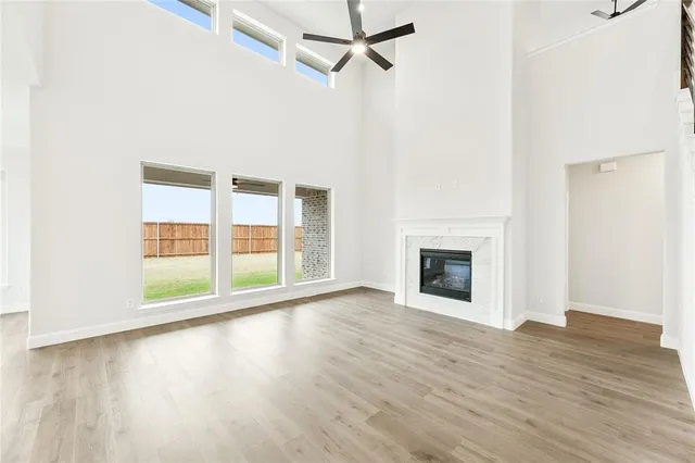 an empty room with wooden floor fireplace and windows