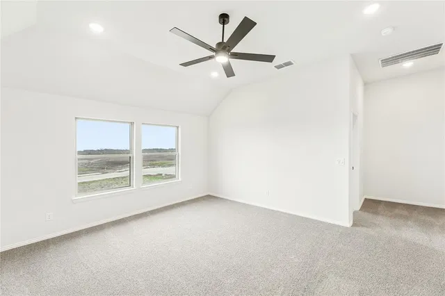 an empty room with ceiling fan and windows
