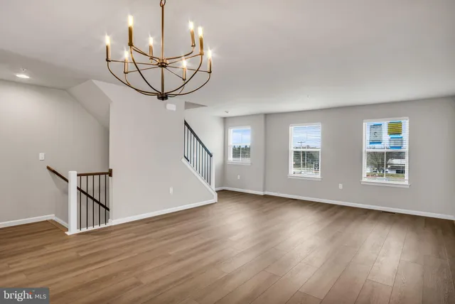a view of a room with wooden floor staircase and a chandelier