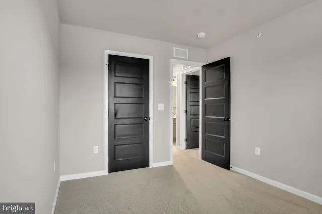 a view of an empty room with closet and entryway