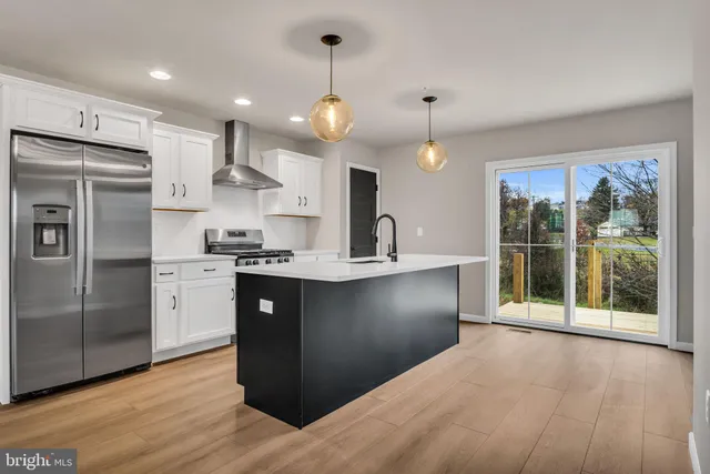 a kitchen with stainless steel appliances granite countertop a refrigerator a sink dishwasher a stove and white cabinets with wooden floor