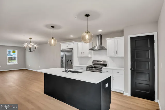 a kitchen with a refrigerator a stove a sink and a wooden floor