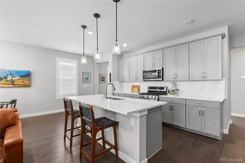 a kitchen with stainless steel appliances granite countertop a sink a stove a refrigerator and island with wooden floor