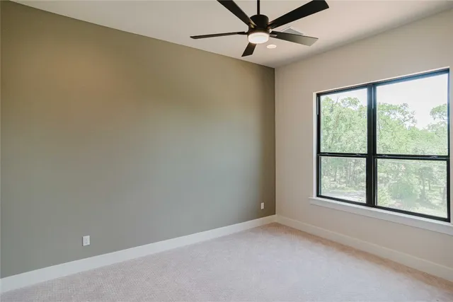 an empty room with windows and ceiling fan
