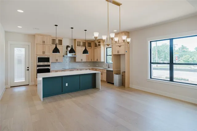a large kitchen with granite countertop a large counter top a sink stainless steel appliances and cabinets