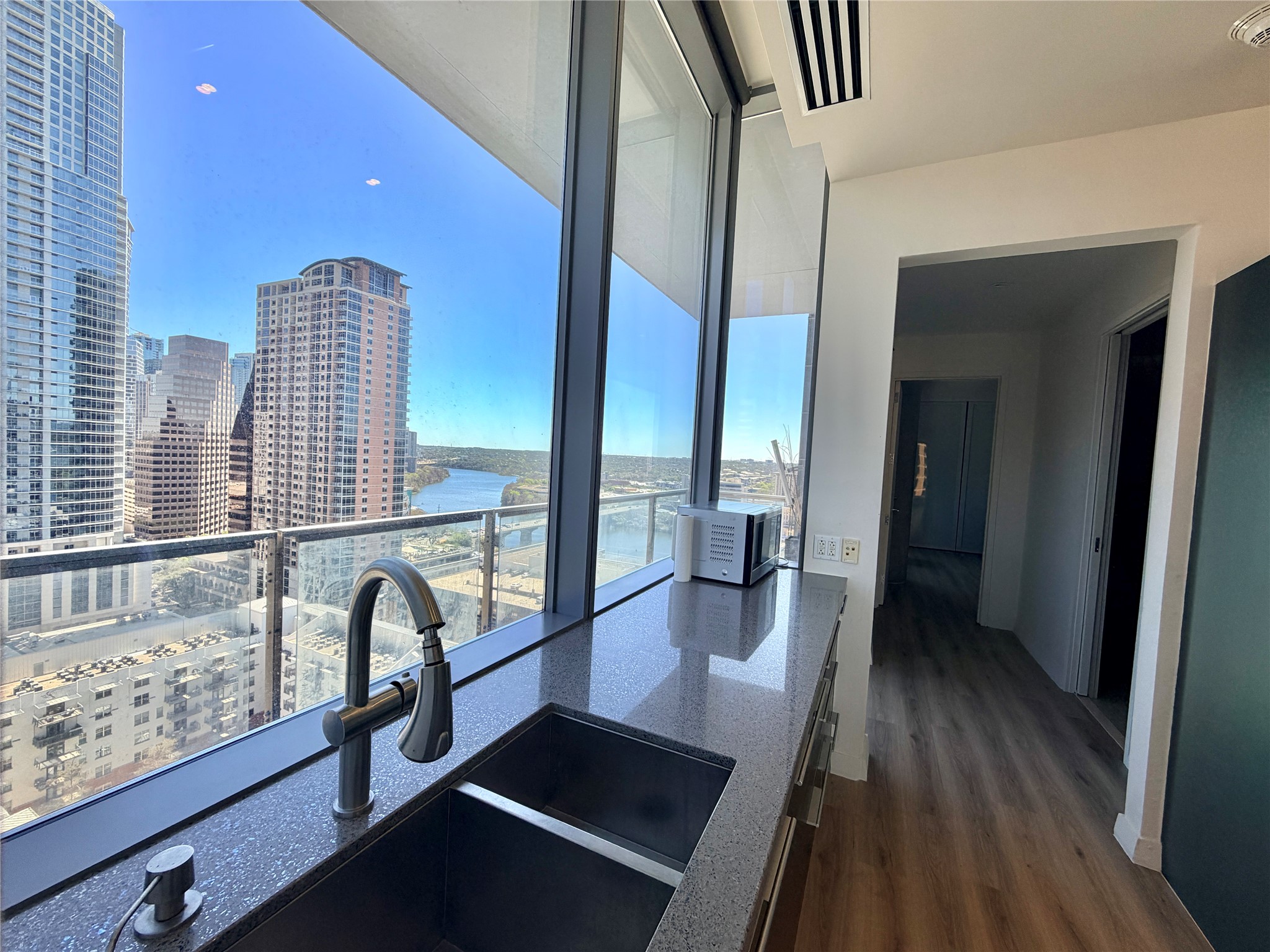 210 Lavaca Street, Unit 1912 Austin, TX 78701 - Photo 10 of 40 Kitchen featuring expansive windows, dark wood-style floors, a city view, dark stone counters, and a water view