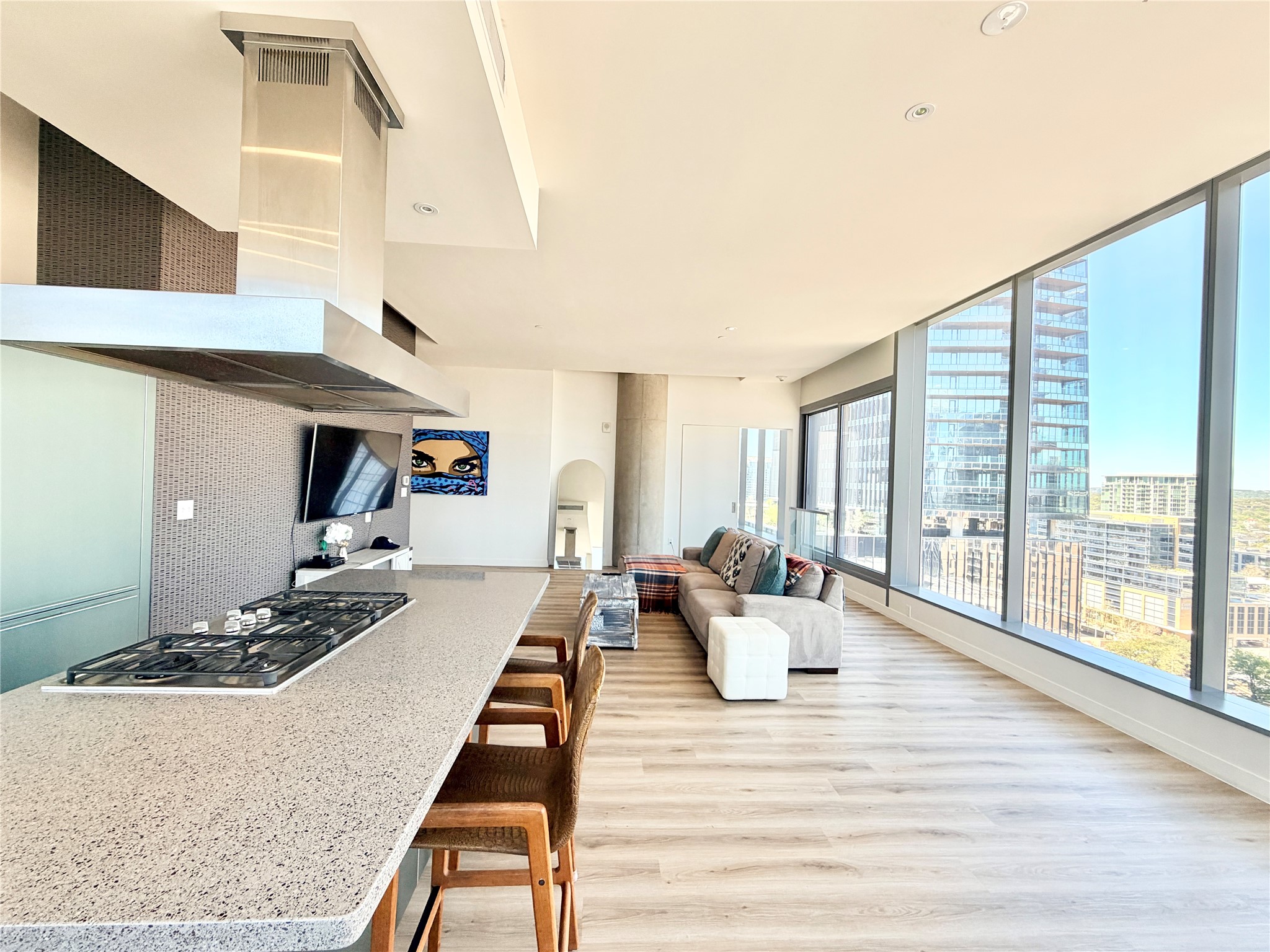 210 Lavaca Street, Unit 1912 Austin, TX 78701 - Photo 23 of 40 Kitchen with extractor fan, light wood-type flooring, arched walkways, stainless steel gas cooktop, and a kitchen bar