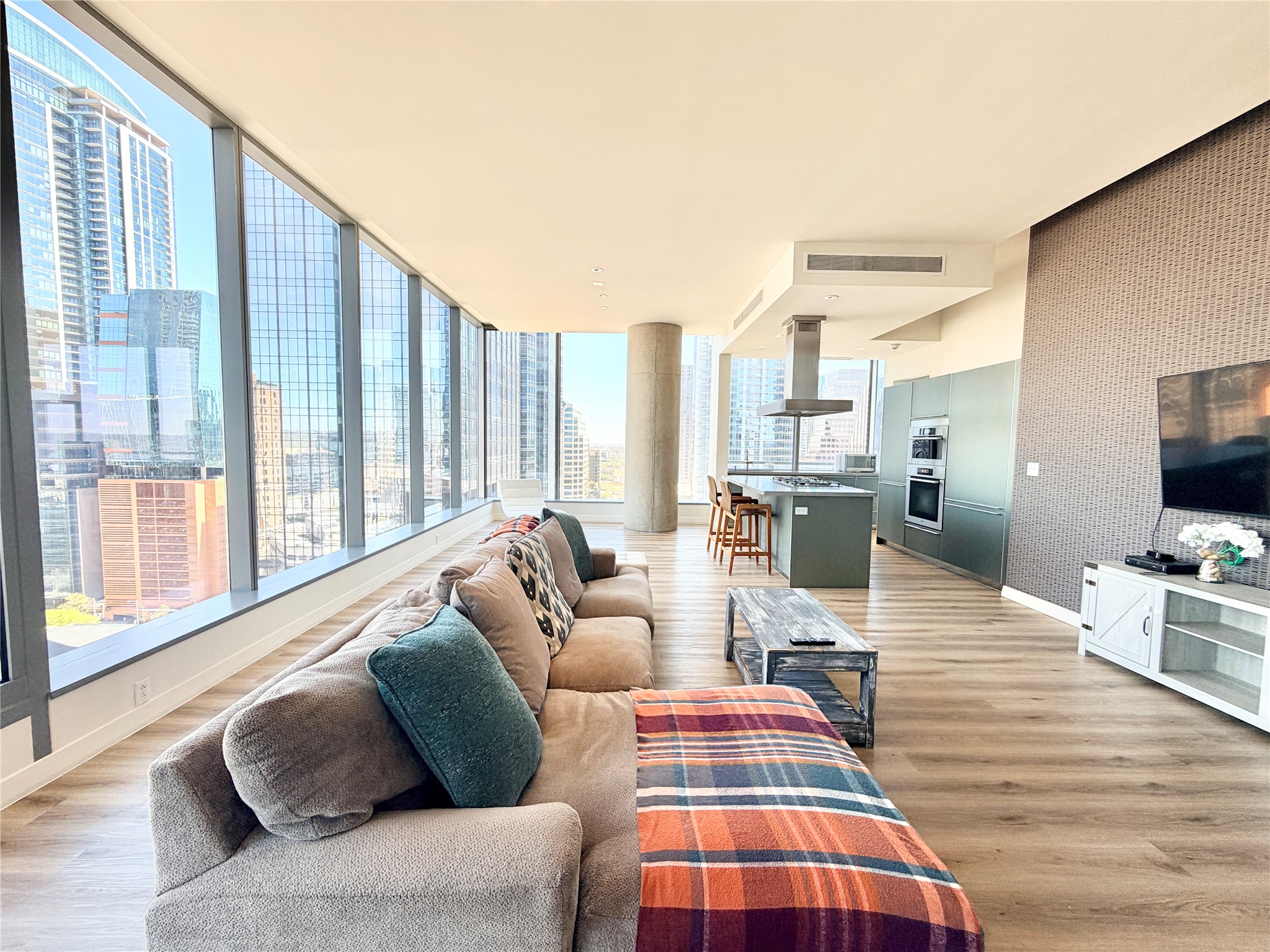 210 Lavaca Street, Unit 1912 Austin, TX 78701 - Photo 4 of 40 Living room featuring a view of city, light wood finished floors, wallpapered walls, and an accent wall