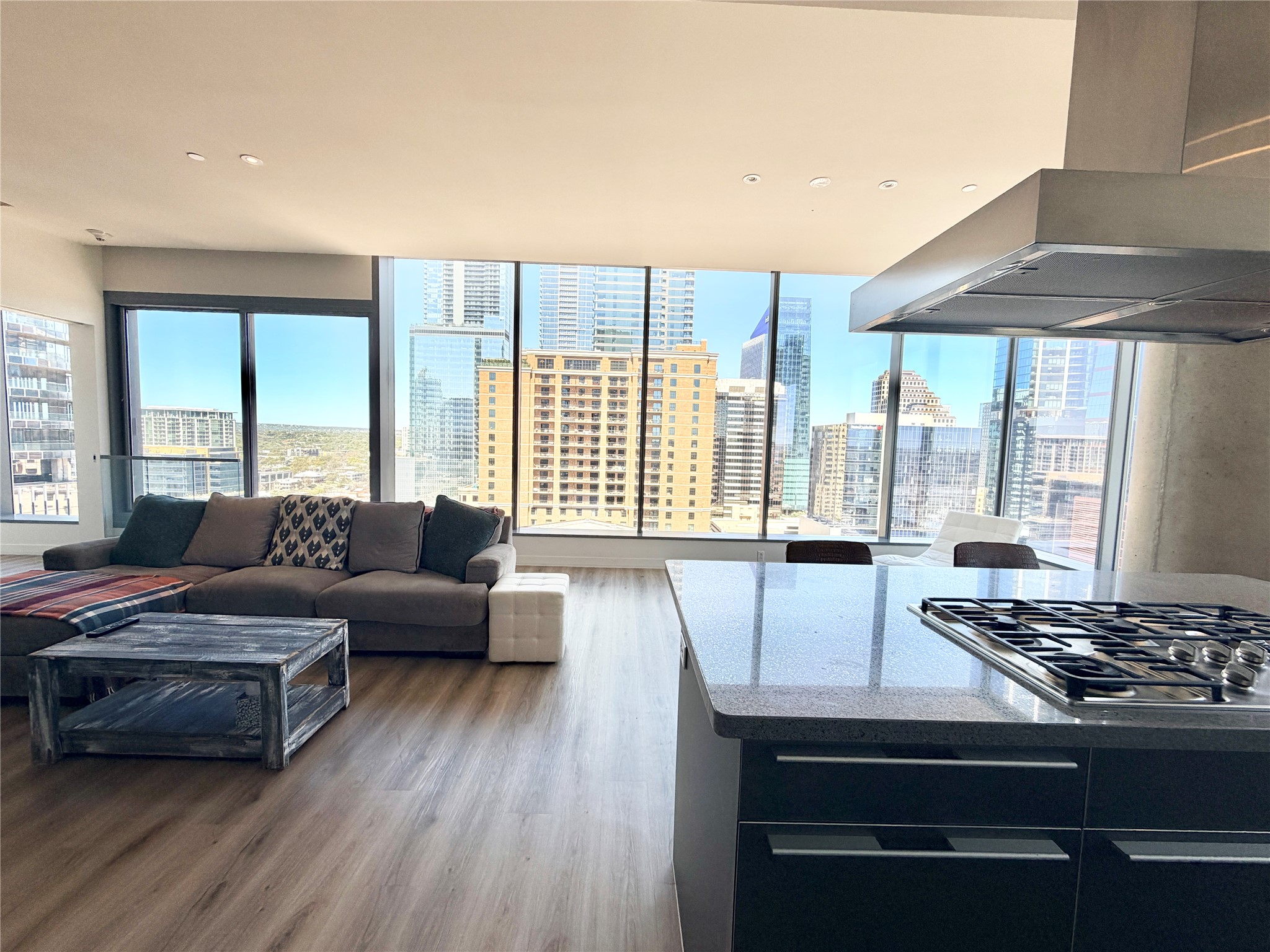 210 Lavaca Street, Unit 1912 Austin, TX 78701 - Photo 40 of 40 Kitchen featuring extractor fan, stainless steel gas stovetop, wood finished floors, a skyline view, and open floor plan
