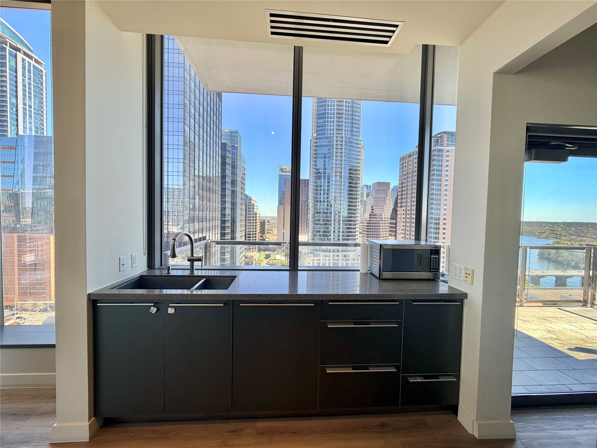 210 Lavaca Street, Unit 1912 Austin, TX 78701 - Photo 7 of 40 Kitchen featuring dark cabinetry, plenty of natural light, dark wood-style floors, modern cabinets, and expansive windows