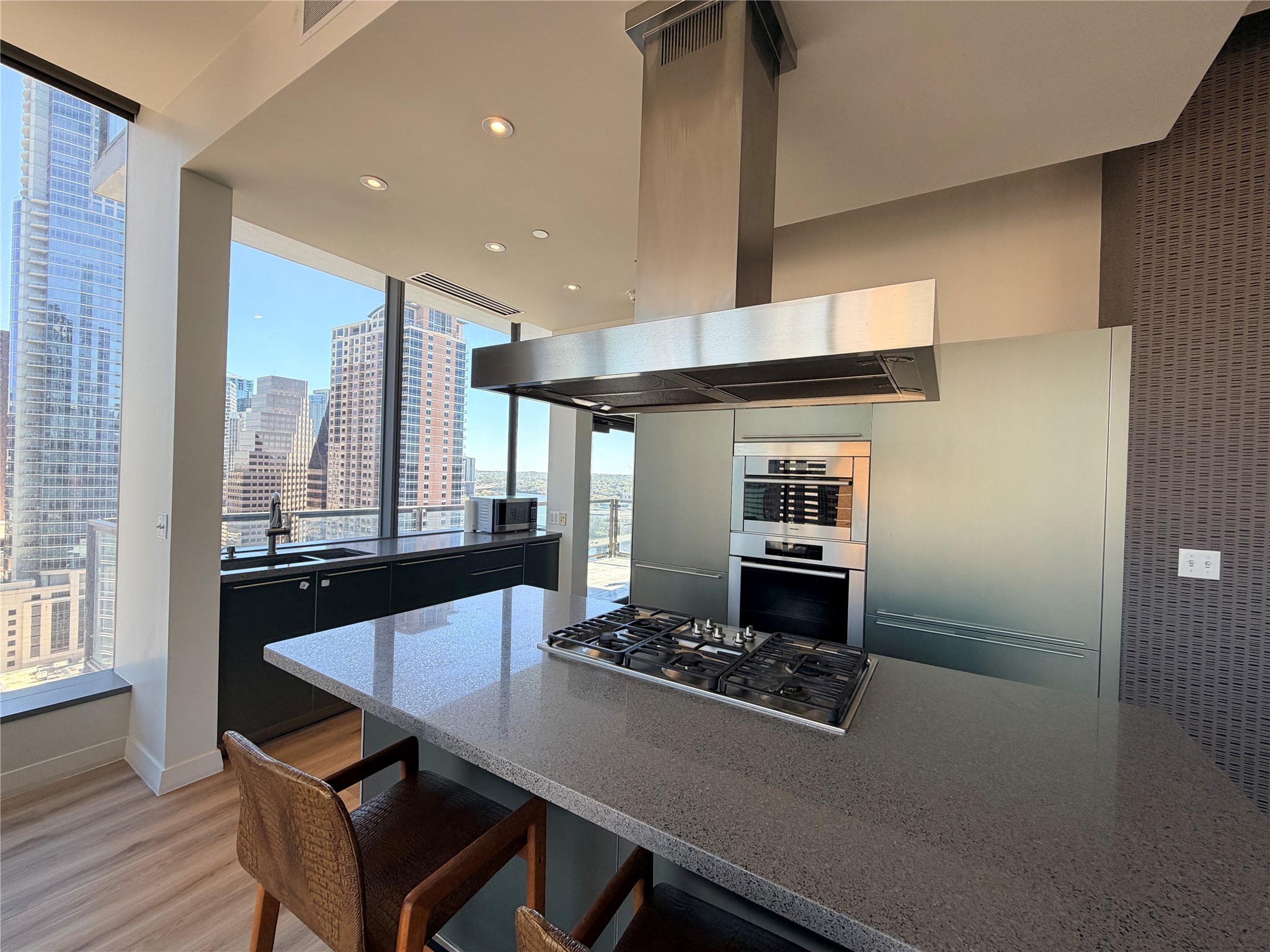 210 Lavaca Street, Unit 1912 Austin, TX 78701 - Photo 8 of 40 Kitchen with a kitchen breakfast bar, island exhaust hood, stainless steel appliances, dark cabinetry, and a skyline view