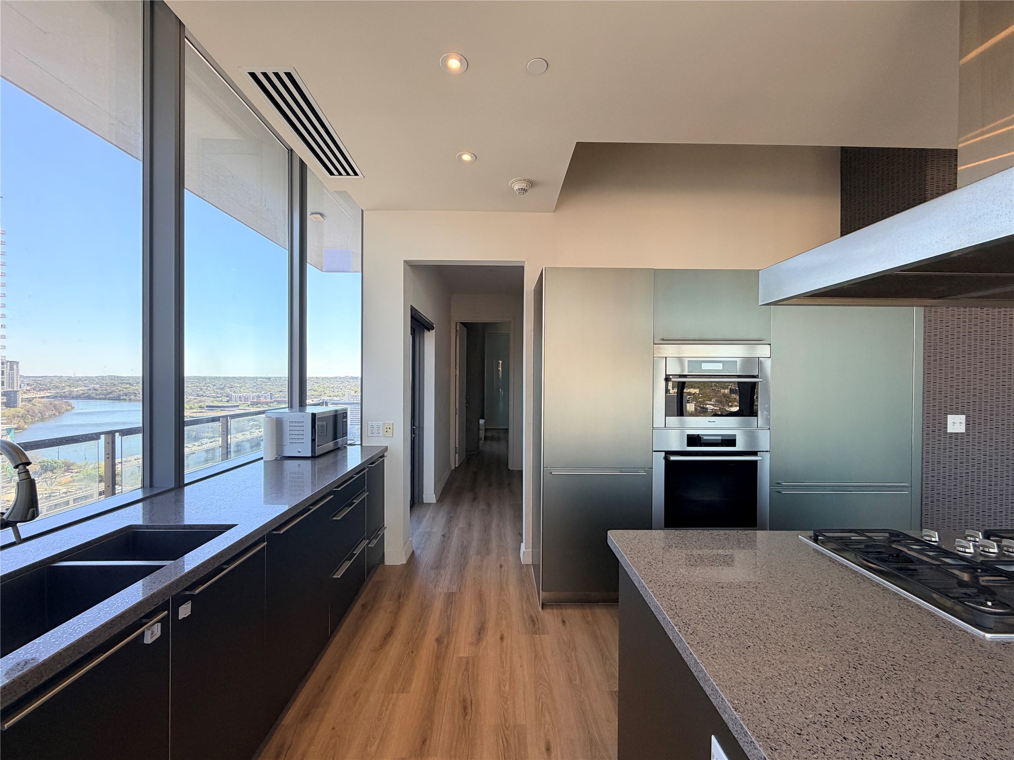 210 Lavaca Street, Unit 1912 Austin, TX 78701 - Photo 9 of 40 Kitchen featuring stainless steel appliances, dark stone counters, light wood-type flooring, dark cabinetry, and recessed lighting