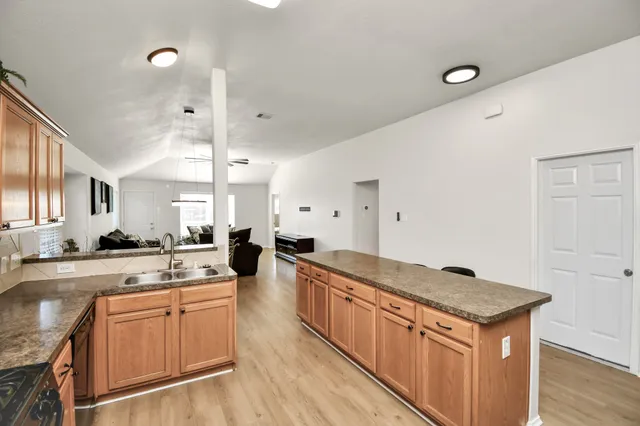 a kitchen with a stove a sink a refrigerator and white cabinets with wooden floor