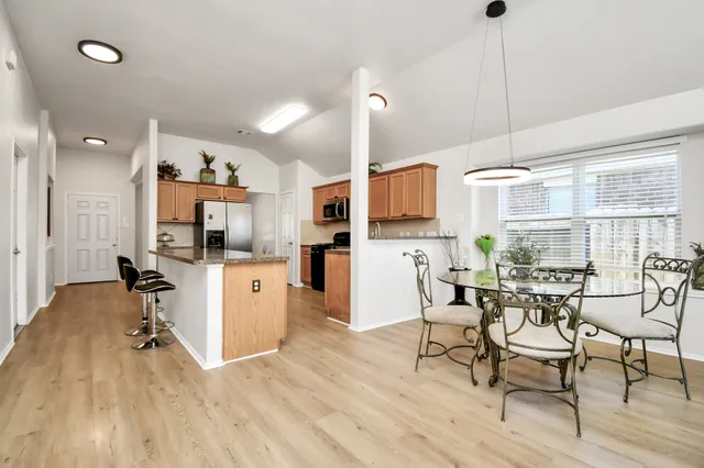 a kitchen with stainless steel appliances a dining table chairs stove refrigerator and cabinets