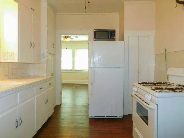 a kitchen with a refrigerator stove and wooden floor