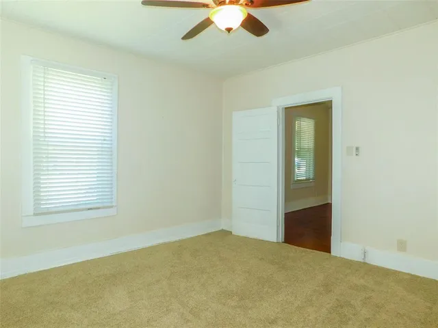 an empty room with chandelier fan and windows