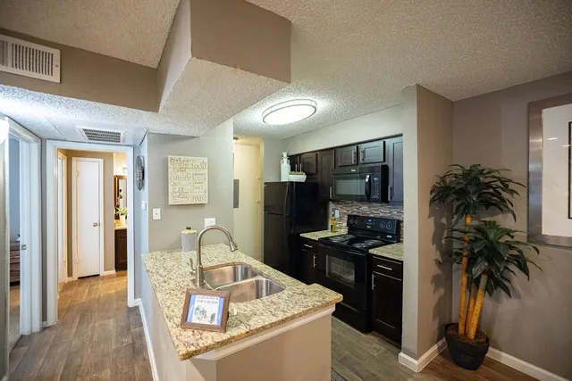 a kitchen with granite countertop a refrigerator stove and sink