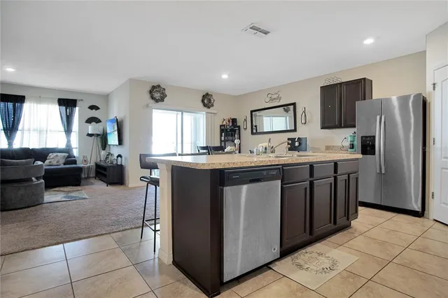 a kitchen with stainless steel appliances granite countertop a table chairs microwave and sink