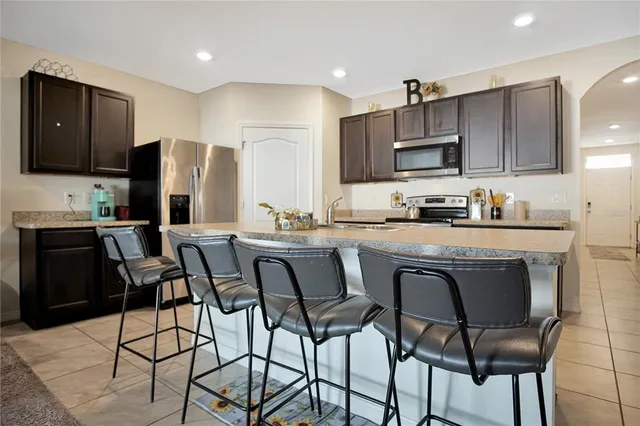 a kitchen with stainless steel appliances a dining table chairs microwave and sink