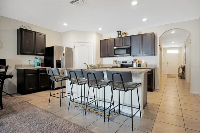 a kitchen with stainless steel appliances kitchen island granite countertop a refrigerator and chairs