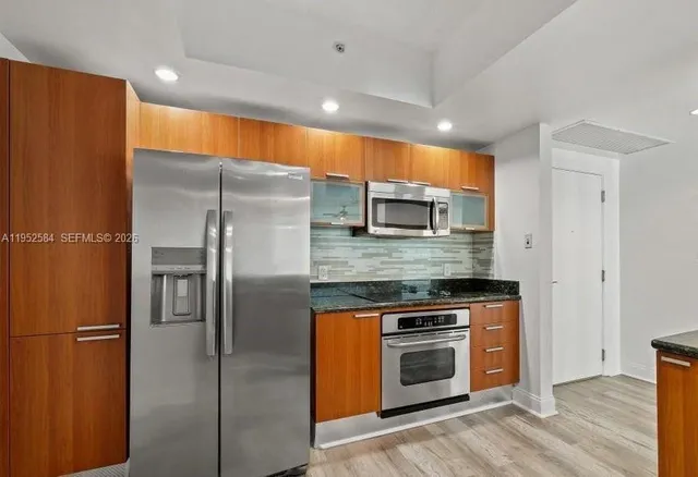 a kitchen with stainless steel appliances granite countertop a refrigerator a stove and a sink