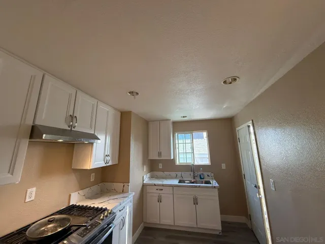 a kitchen with granite countertop a sink stove and refrigerator