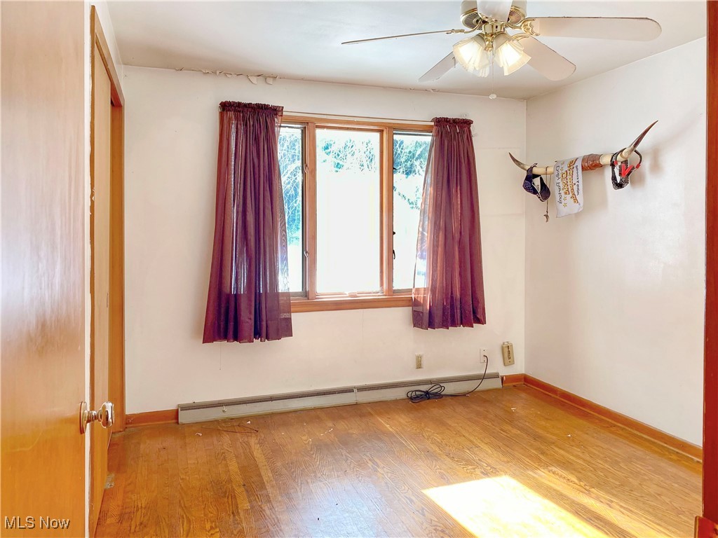 1034 Straub Road West Mansfield, OH 44904 - Photo 9 of 27 Spare room featuring ceiling fan, light hardwood / wood-style flooring, and a baseboard radiator