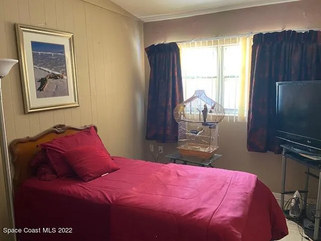 a bedroom with a bed and a flat tv screen on dresser